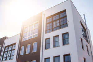 Cute block shaped white and brown apartment buildings from low angle view with bright sunlight over the roof